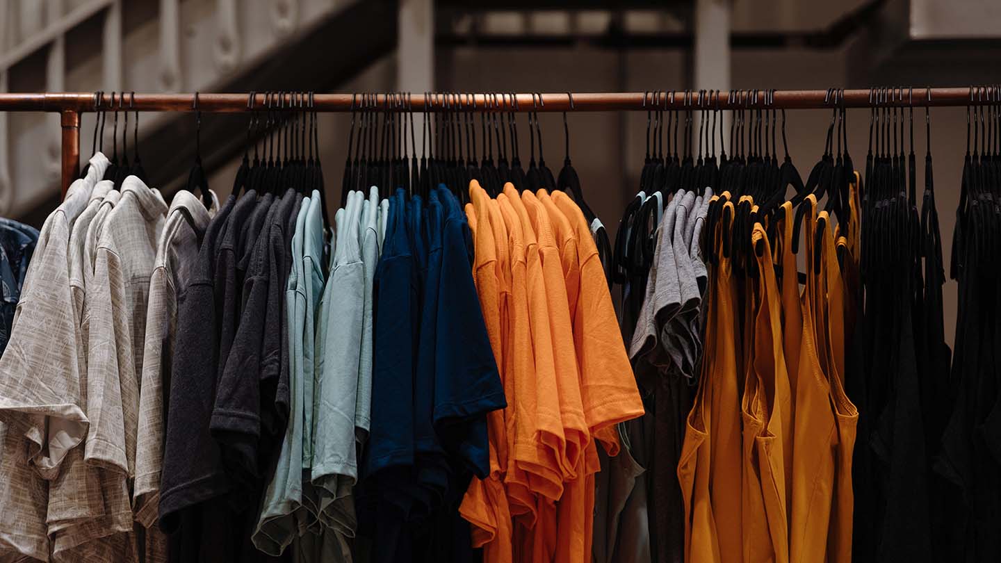 Clothing rack with various colored shirts hanging on it.